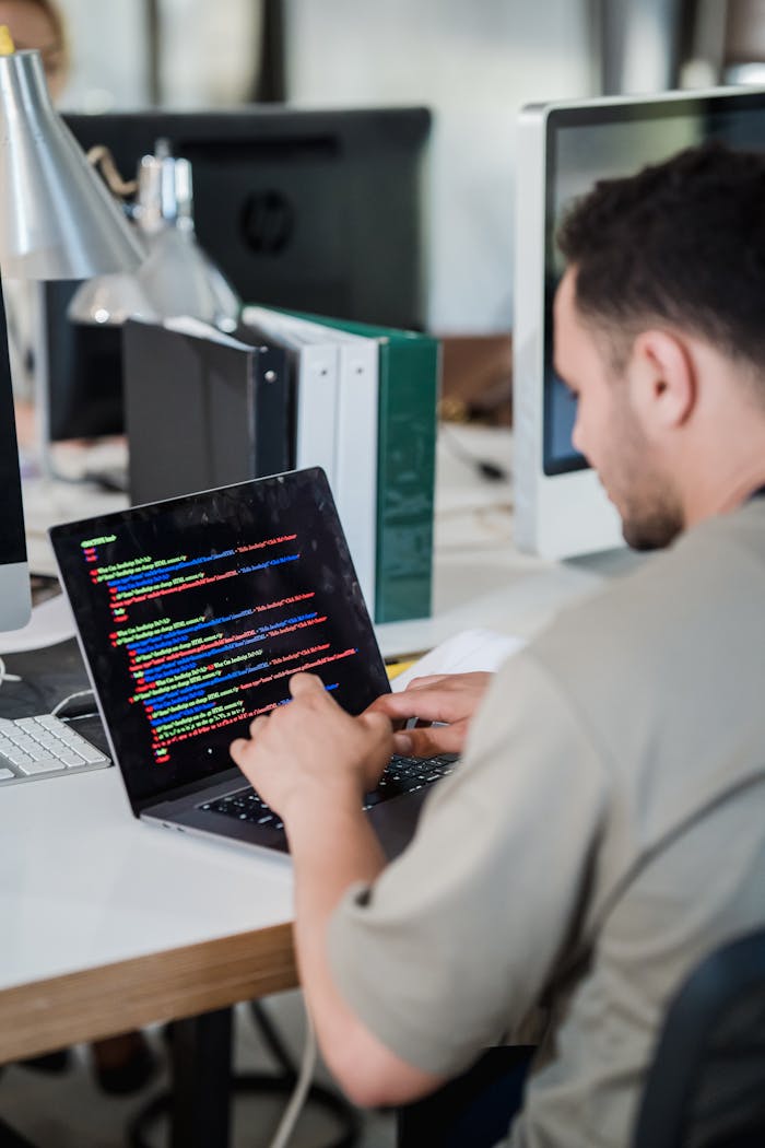 our-experience Focused software developer typing code on a laptop in a modern office setting.